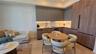 Kitchen featuring flat-panel cabinetry in matte grey and wood-finish, light-toned stone-finish countertops, integrated refrigerator, and under-cabinet