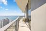 Curved exterior balcony featuring tile flooring, a glass-panel railing, and floor-to-ceiling glass sliding doors