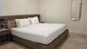 Built-in wood-finish platform bed frame with integrated side tables, wood-finish flooring, and wall-mounted oval mirror