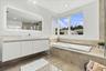 Modern bathroom featuring a wall-mounted floating vanity with a rectangular sink, expansive LED-backlit mirror, large-format tile flooring, built-in s