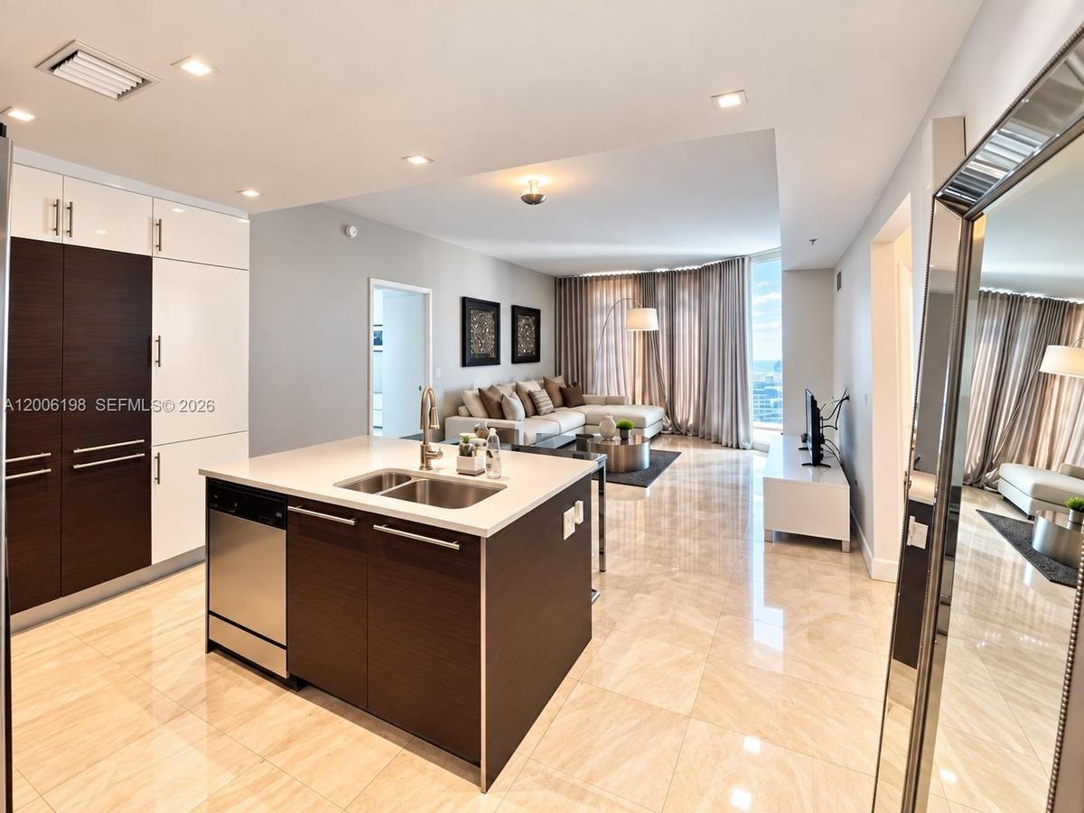 Modern kitchen featuring high-contrast cabinetry, stone-finish countertops, stainless steel undermount sink, and recessed lighting throughout, complem
