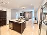 Modern kitchen featuring high-contrast cabinetry, stone-finish countertops, stainless steel undermount sink, and recessed lighting throughout, complem