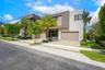 Modern two-story architectural exterior featuring a stucco facade, multi-tonal earth-tone finish, integrated multi-car garage, and concrete paver driv