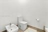 White porcelain toilet and matching bidet featuring chrome hardware, complemented by neutral tile flooring