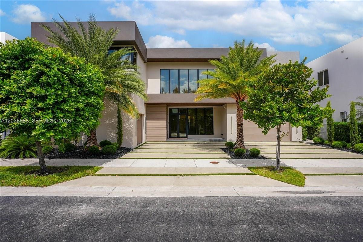 Contemporary architectural exterior featuring a concrete paver driveway with turf accents, expansive glass windows, and clean, horizontal-lined facade