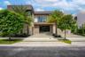 Contemporary architectural exterior featuring a concrete paver driveway with turf accents, expansive glass windows, and clean, horizontal-lined facade
