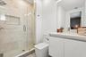 Bathroom featuring a walk-in shower with stone tile surround, integrated shower niche, glass enclosure, floating vanity with an integrated basin, and 