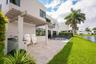 Stucco exterior featuring a covered pergola, stone-paved patio, built-in outdoor kitchen, and a pool with perimeter fencing