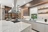 Kitchen featuring a large island with a surface-mounted cooktop, stainless steel vent hood, floor-to-ceiling wood-finish cabinetry, stone-patterned ba