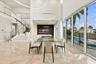 Double-height ceilings, floor-to-ceiling glass sliding doors, polished tile flooring, floating staircase with glass railings, and circular LED pendant