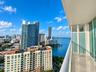 Private balcony with tile flooring, frosted glass privacy panels, and an aluminum railing, showcasing a water and skyline panorama