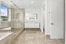 Bathroom featuring a large glass-enclosed walk-in shower, floating vanity with an integrated sink, rectangular illuminated wall mirror, and large-form