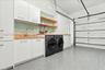 Garage utility area featuring white cabinetry, wood-finish countertops, a stainless steel sink with a chrome faucet, light green subway tile backsplas