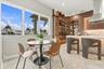 Large windows featuring exterior palm tree and pergola scenery, custom wood-finish cabinetry with integrated wine storage, glass-front display shelvin
