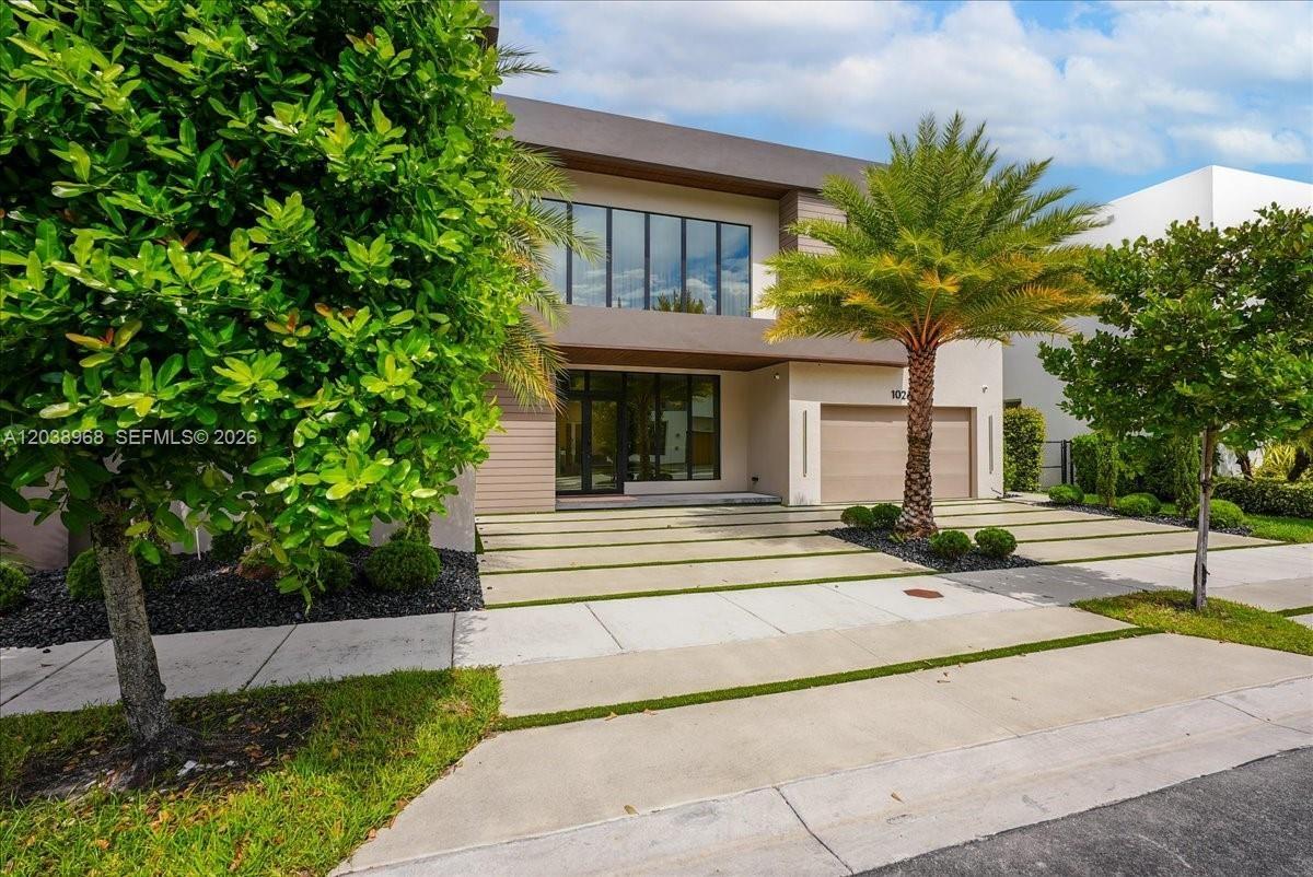 Contemporary exterior featuring clean horizontal lines, expansive multi-pane windows, a recessed entryway, an integrated garage, and a segmented concr