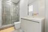 Modern bathroom featuring a floating vanity with a light-tone countertop, an integrated sink, a large wall-mounted mirror, and a walk-in shower with t
