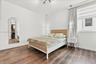 Wood-finish flooring, arch-top wall mirror, adjustable window blinds, ceiling-mounted track lighting, and dual minimalist pendant lights