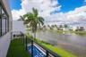 Balcony featuring synthetic turf flooring and black metal railing, overlooking a private pool and water feature