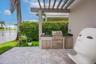 Outdoor kitchen featuring a stone countertop, built-in stainless steel grill, under-counter refrigeration, and sink, situated under a wood-beam pergol