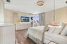 Room featuring wood-finish flooring, textured wall treatments, minimalist disc-style flush mount ceiling lighting, and suspended metallic pendant ligh