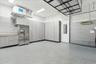Garage interior featuring epoxy flooring, wall-to-wall built-in cabinetry, stainless steel refrigerator, overhead storage rack, and corrugated metal w