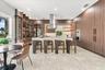 Modern kitchen featuring full-height wood-finish cabinetry, a large central island with stone surfacing, stainless steel range hood, integrated wall o