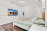 Wood-finish flooring, textured arched wall mirror, woven-texture headboard, and contemporary cylindrical pendant lighting