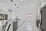 Kitchen featuring a waterfall-edge island with stone-finish countertops, white cabinetry, integrated stainless steel appliances, matte black plumbing 