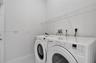 Laundry area featuring white appliances, textured walls, and integrated wire shelving
