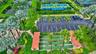 Aerial perspective of recreational facilities including shuffleboard courts, tennis courts, paved parking area, and mature landscaping
