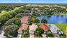Aerial perspective of a single-story residence featuring a tiled roof, paver driveway, and direct water frontage on a lake