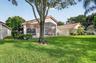 Stucco exterior with a tile roof, screened-in lanai, and an expansive lawn