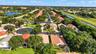 Aerial perspective of the residential community featuring tile roofing, mature canopy trees, paved roadways, and proximity to canal infrastructure