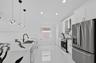 Kitchen featuring an expansive center island with high-contrast stone countertops, stainless steel appliances, white cabinetry, recessed lighting, and