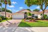Single-story residence featuring a tile roof, brick-paver driveway, double-car garage, and an arched entryway with decorative metal security door