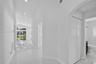 Hallway featuring polished light-toned floor tile, recessed ceiling lighting, arched wall detailing, and dual-panel interior doors
