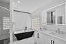 Bathroom featuring a black-and-white freestanding soaking tub with floor-mounted faucet, glass block windows, a dual-sink vanity with white countertop