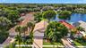 Aerial perspective featuring tile-roofed residences, paver driveways, and proximity to a waterfront