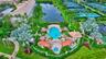 Aerial perspective of a community pool area featuring a paver deck, multiple shade structures, integrated spa, and surrounding palm landscaping