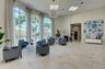 Grand foyer featuring towering arched floor-to-ceiling windows, high-contrast light stone flooring, a spherical crystal chandelier, and neutral wall t
