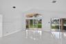 Living area featuring vaulted ceilings, polished tile flooring, and oversized glass sliding doors with a transom window opening to a screened lanai
