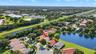 Aerial view of a residential property featuring a tiled roof and proximity to a community lake
