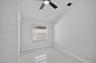 Vaulted ceilings, large-format tile flooring, a multi-blade ceiling fan with integrated lighting, and a single-pane window with horizontal blinds
