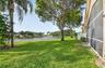 Expansive backyard featuring a pond-side location, mature landscaping, manicured lawn, and a screened-in lanai enclosure