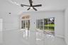 Vaulted ceiling featuring a ceiling fan with integrated lighting, oversized tile flooring, and sliding glass doors with arched transom windows