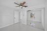 Neutral-toned flooring, sliding mirrored closet doors, and ceiling fan with integrated lighting
