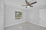 Interior space featuring large-format tile flooring, a multi-pane window with a grid pattern, a ceiling fan with integrated lighting and wood-finish b