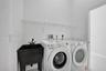 Utility area featuring a deep basin sink with a matte black faucet, wall-mounted wire shelving, and dedicated hookups for laundry appliances