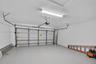 Two-car garage featuring a sectional metal door, finished epoxy flooring, and linear LED lighting