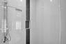 Shower enclosure featuring large-format white wall tile, a vertical decorative stone accent strip, a built-in recessed shelf, and a stainless steel sh